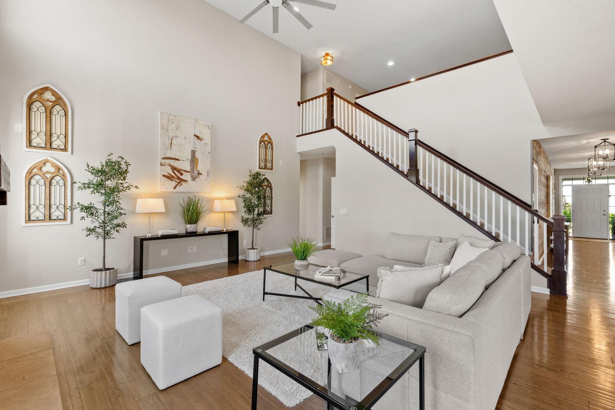 A dramatic open staircase and towering ceilings create an airy, grand atmosphere in the spacious main living room.