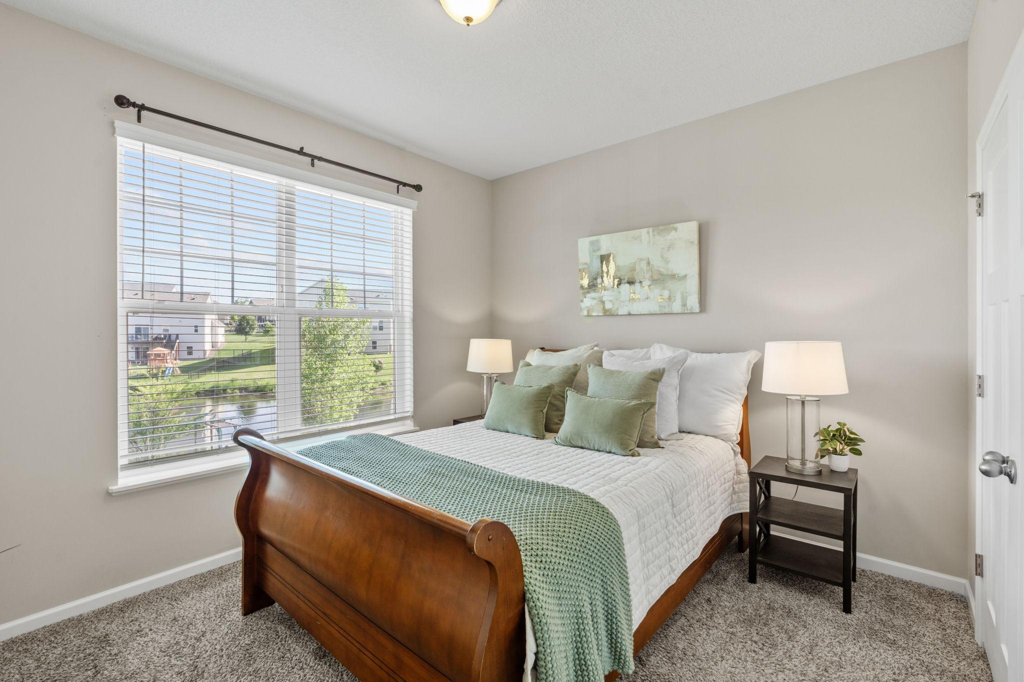 A spacious bedroom retreat featuring plush carpeting, a wide window with peaceful views, and generous closet space.