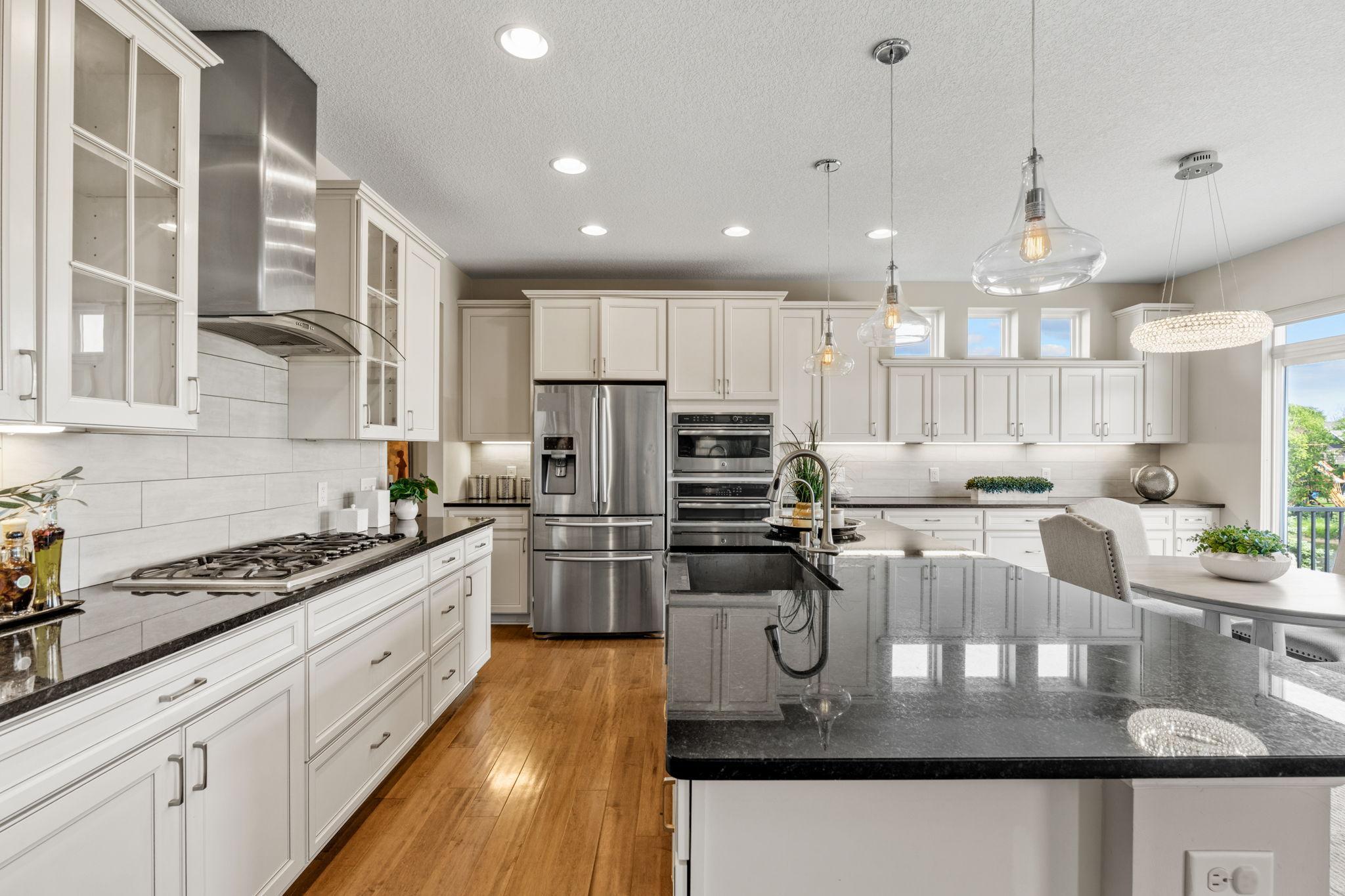 Striking dark granite countertops contrast beautifully with the bright tile backsplash and under-cabinet accent lighting.