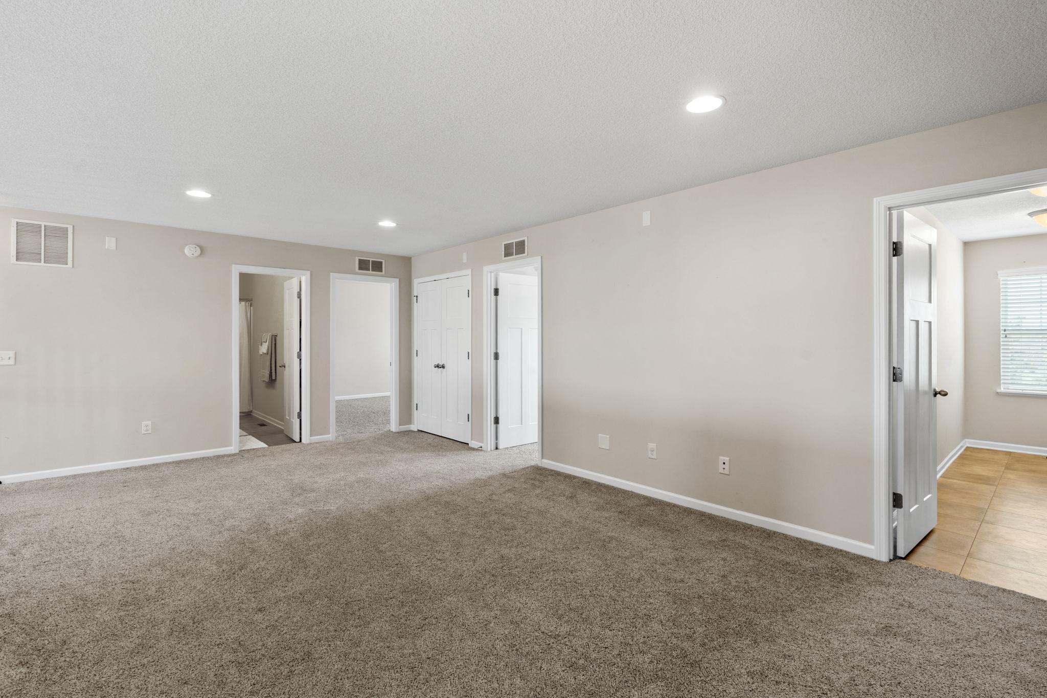 The upper-level landing keeps doorways wide and transitions seamless between the bedrooms, full bathrooms, and central laundry area.