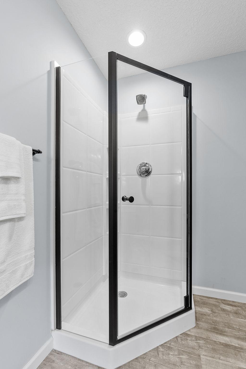 The glass-enclosed basement shower stall features a clean, low-maintenance surround with built-in corner storage ledges.