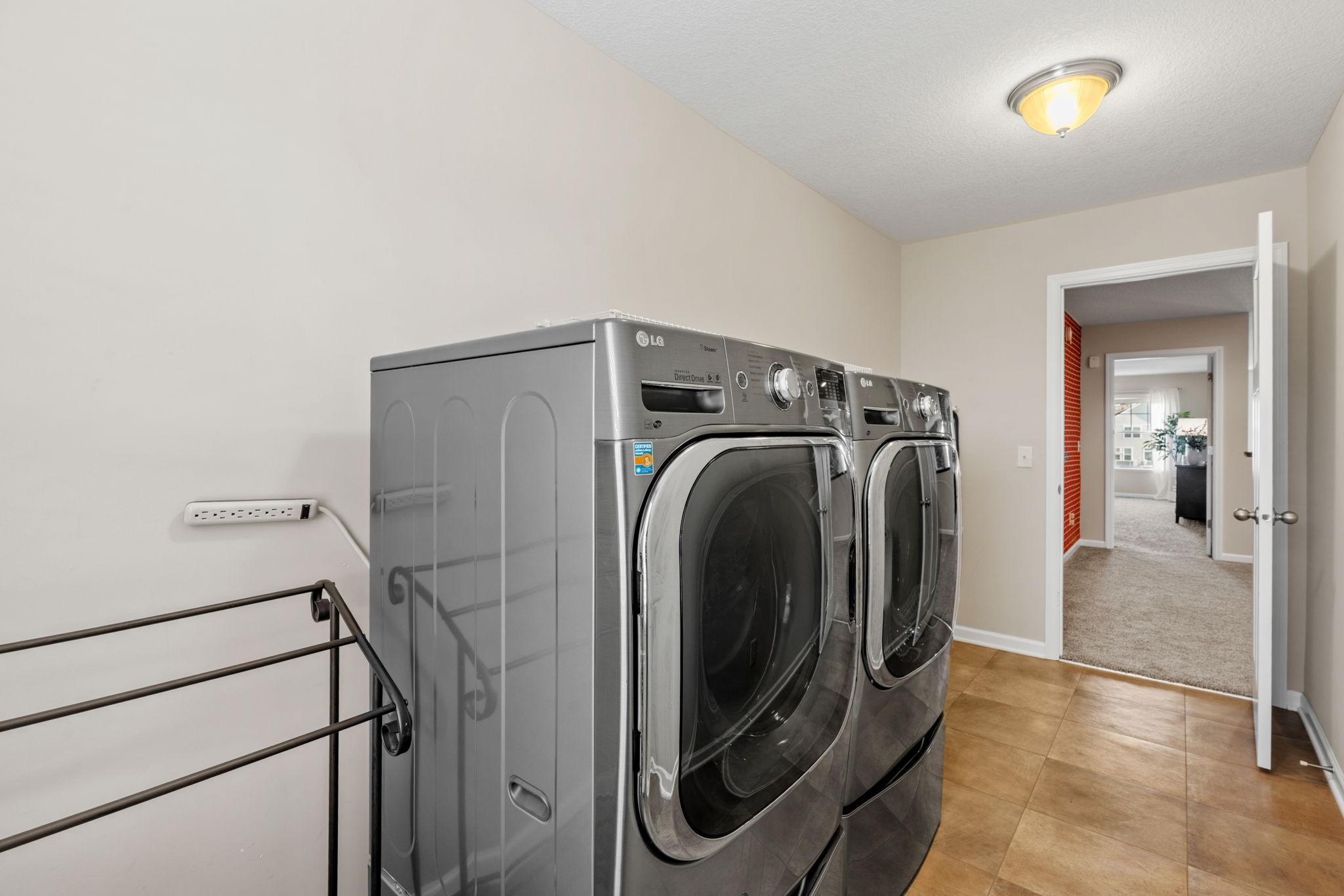 Front-loading metallic gray laundry units anchor this spacious room, making chores a breeze while tucked out of sight from main living areas.