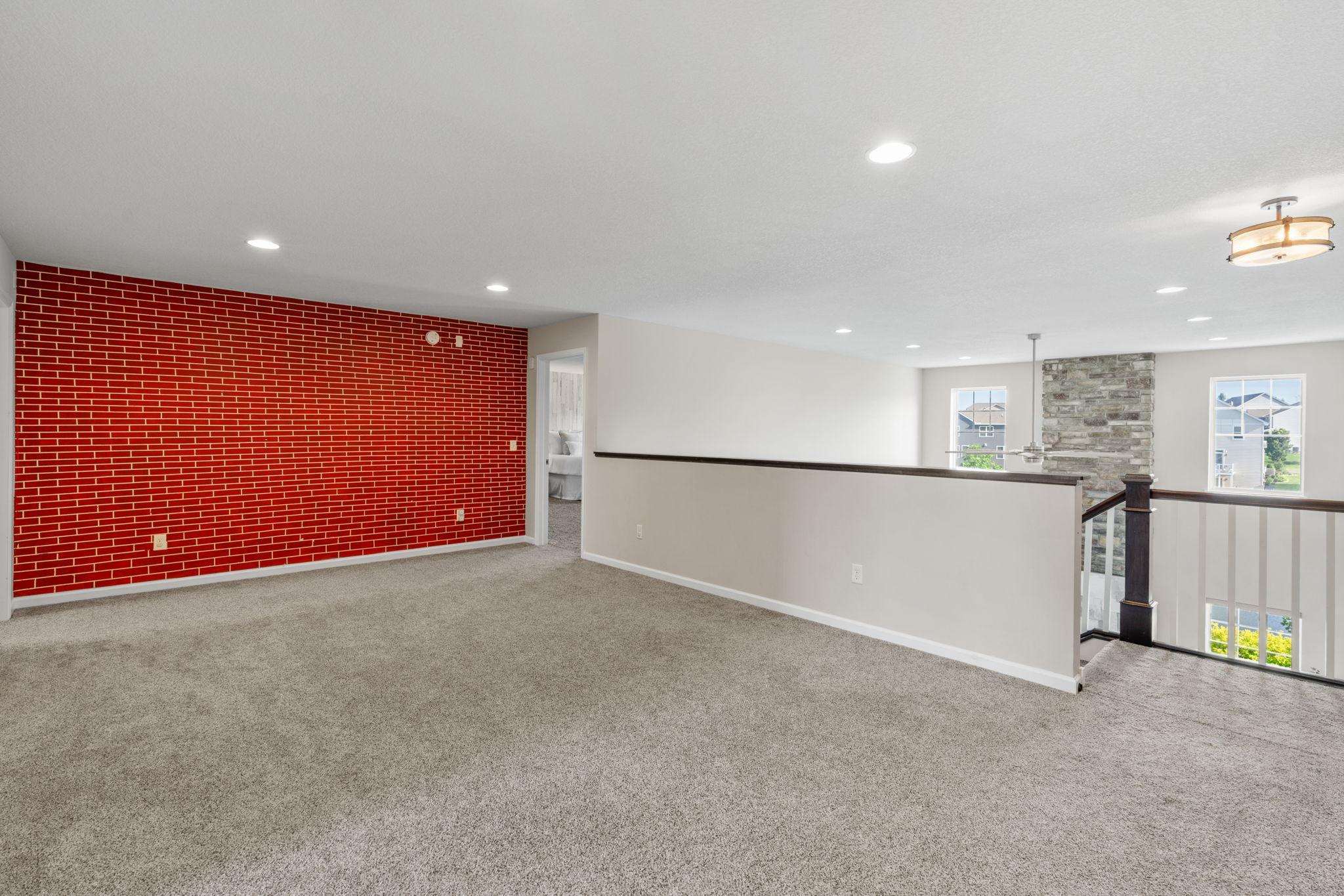 The sprawling loft area features a striking crimson brick-style accent wall, adding incredible visual warmth and character.