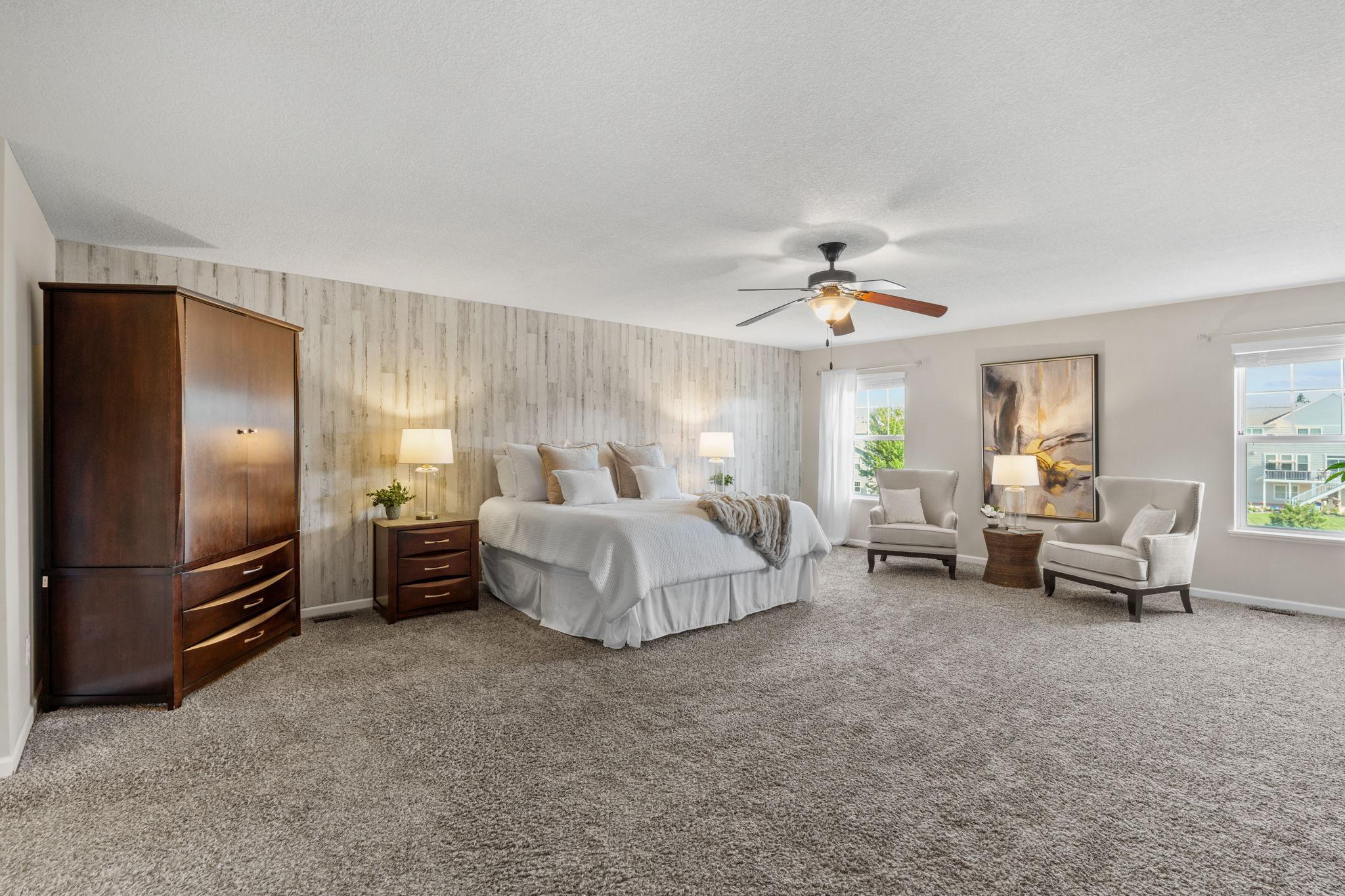 Welcome to the expansive primary bedroom sanctuary, showcasing a beautiful whitewashed wood-panel accent wall and plush neutral carpeting.