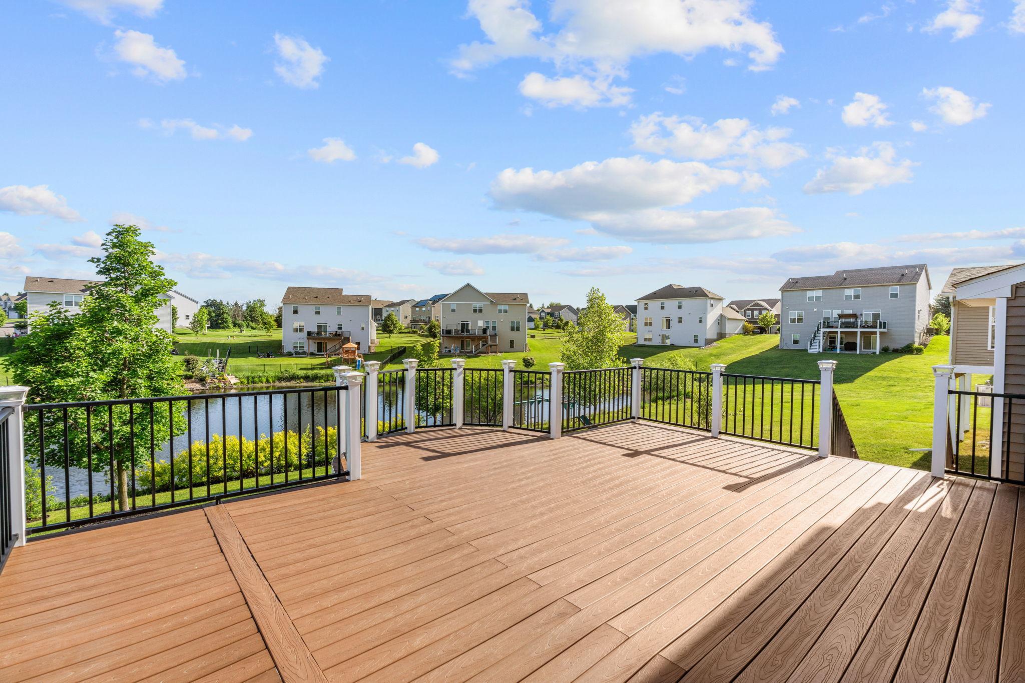 The massive upper deck features low-maintenance composite planks, stylish black railings, and a grand, open-air layout.