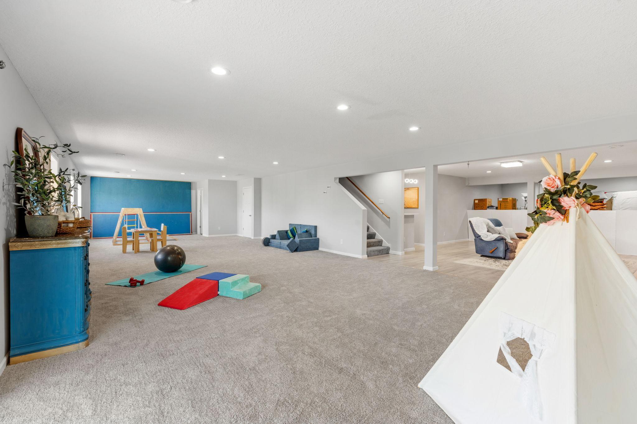 Multiple windows and full-view glass doors keep the lower level feeling bright and airy, seamlessly connecting indoor entertainment with the outdoors.