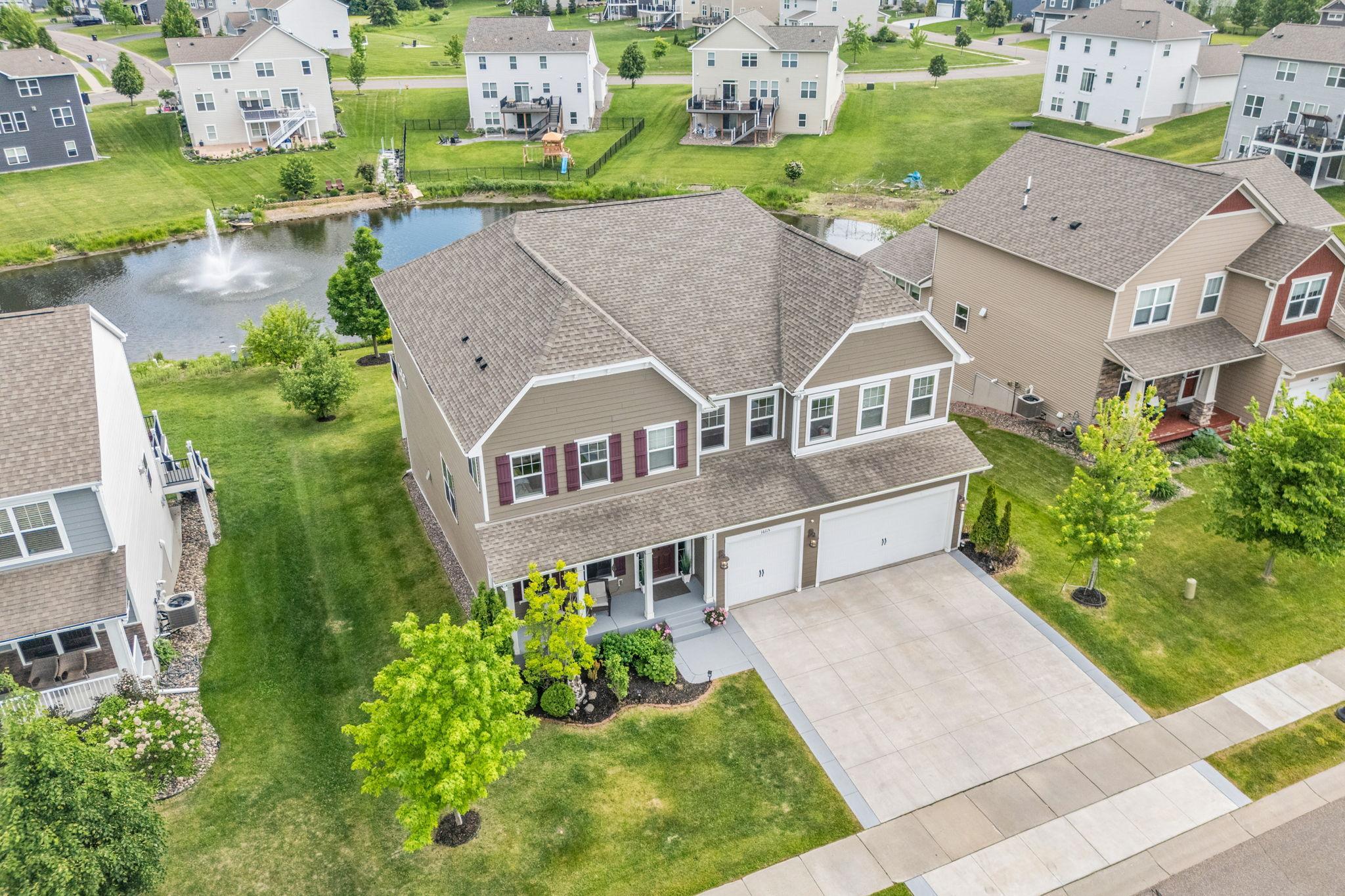 A high-angle front view showcasing the grand exterior, pristine three-car cement driveway, and manicured landscaping that welcomes you home.