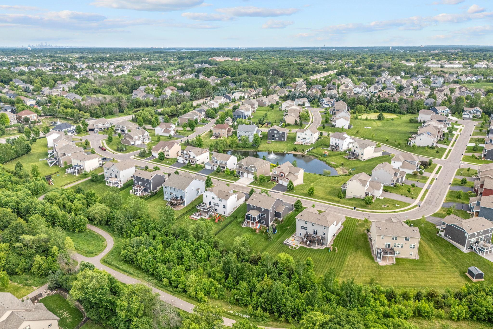 An expansive aerial view highlighting the meticulously planned community, surrounded by mature trees, walking paths, and beautiful open green spaces.