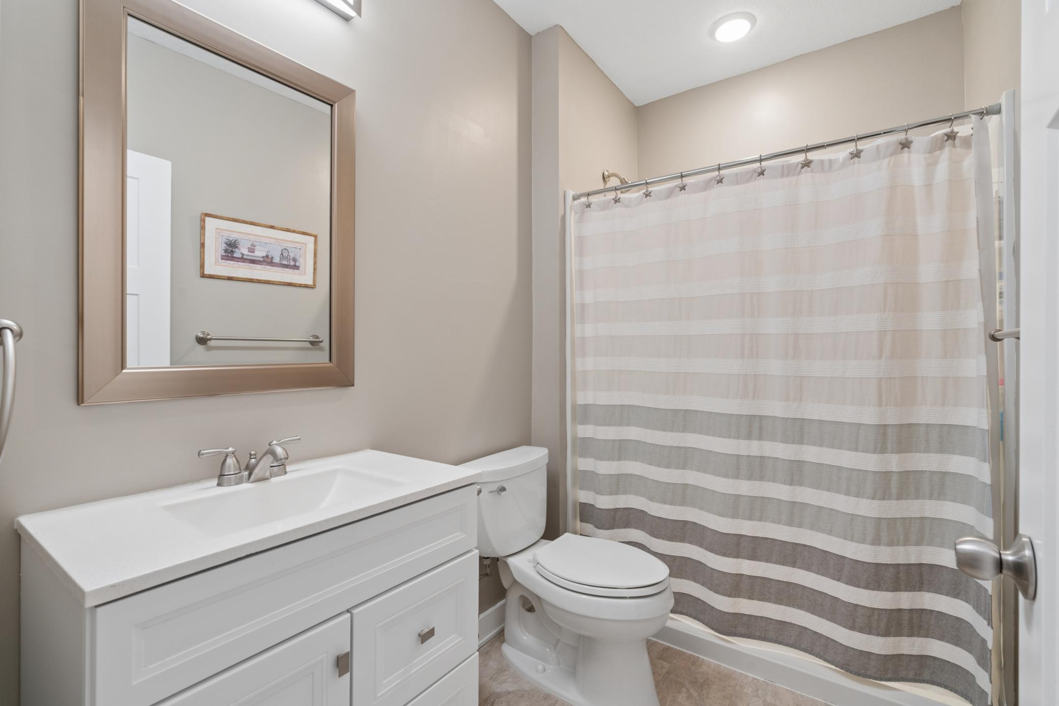 Modern finishes with a sleek vanity, framed mirror, and neutral tile — a clean, stylish design.