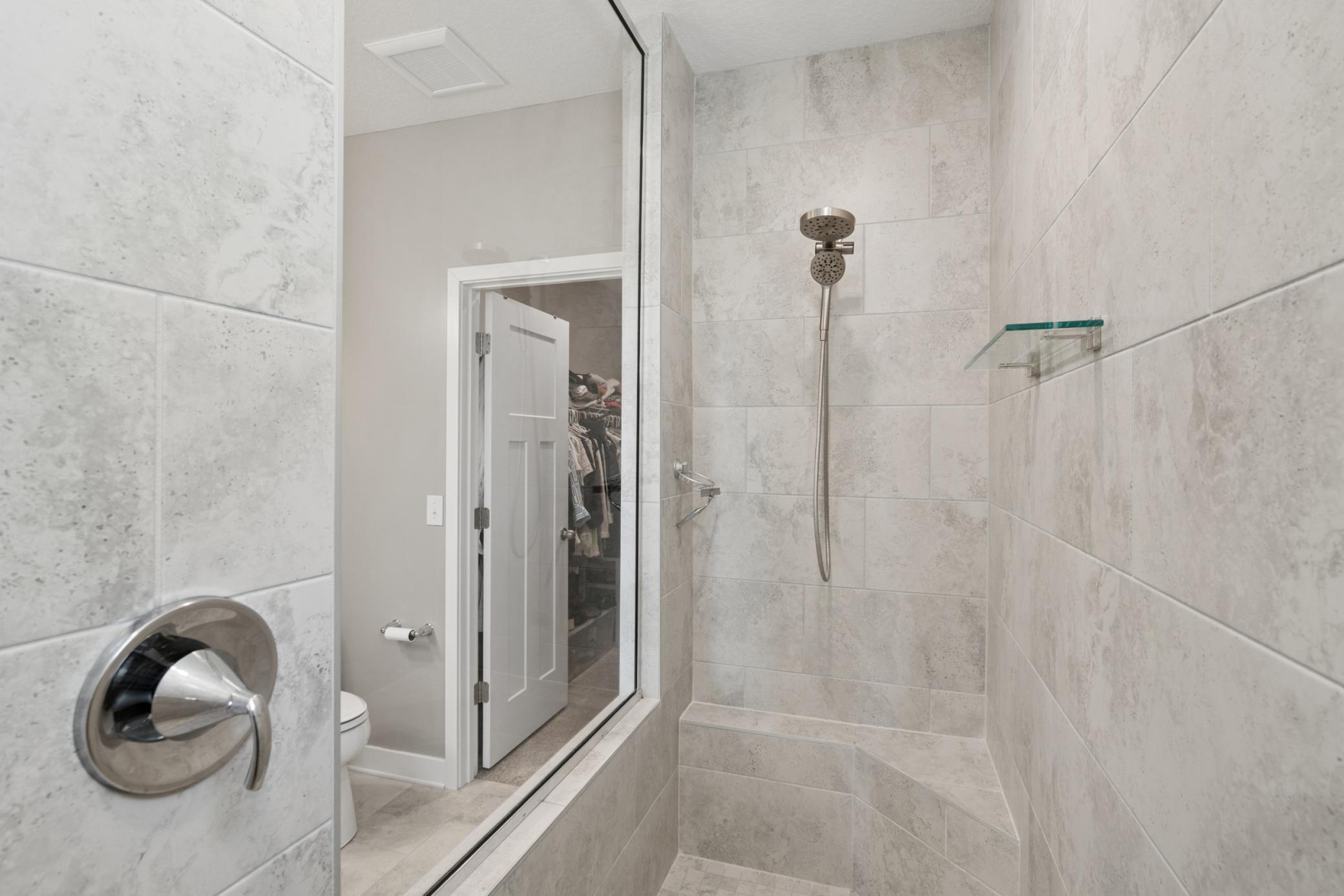Elegant tilework, built-in bench, and glass enclosure — spa-like comfort in your own home.