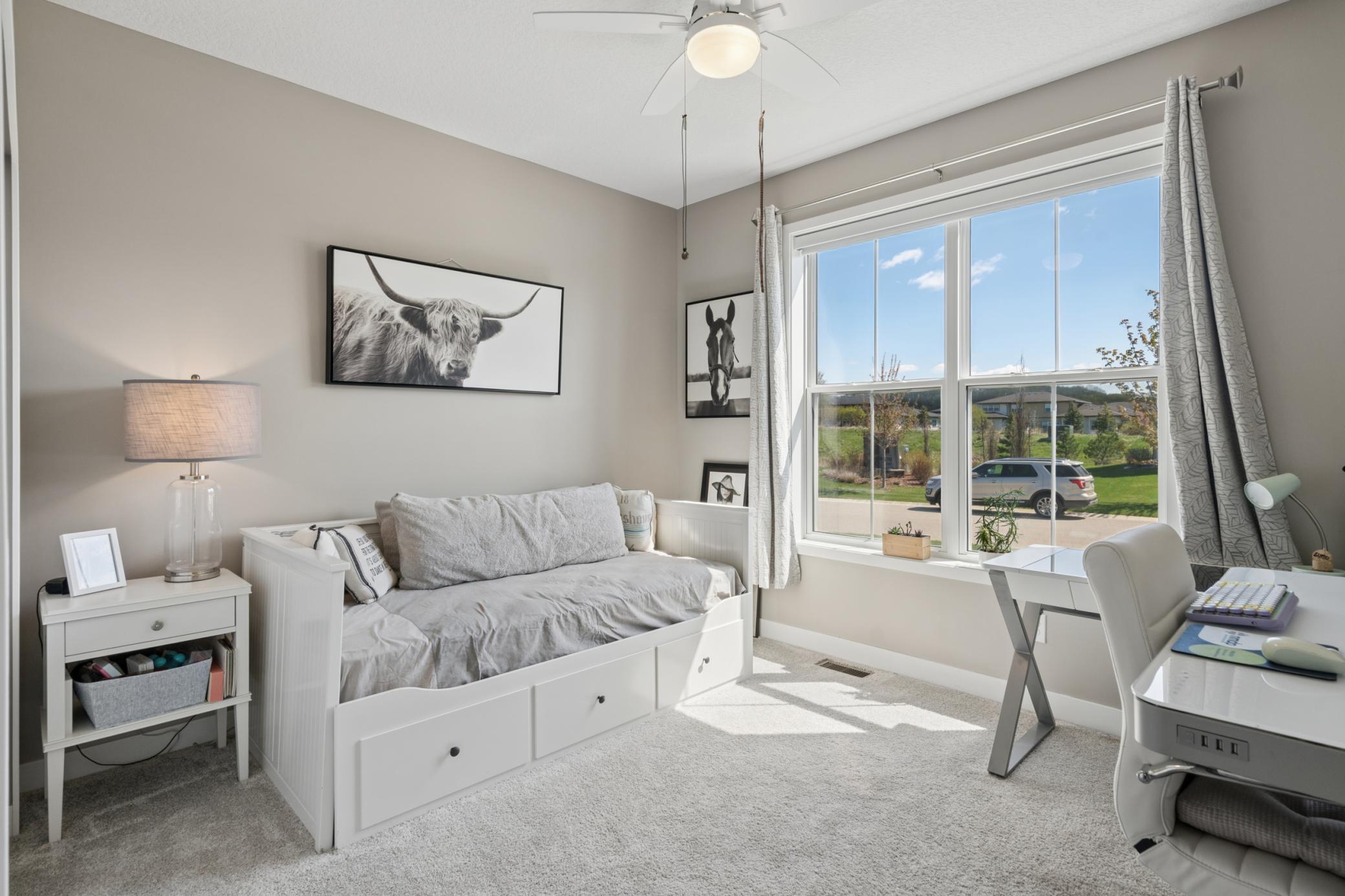 Crisp white furniture, large window, and soft carpet create a peaceful, sunlit space for guests or a home office.