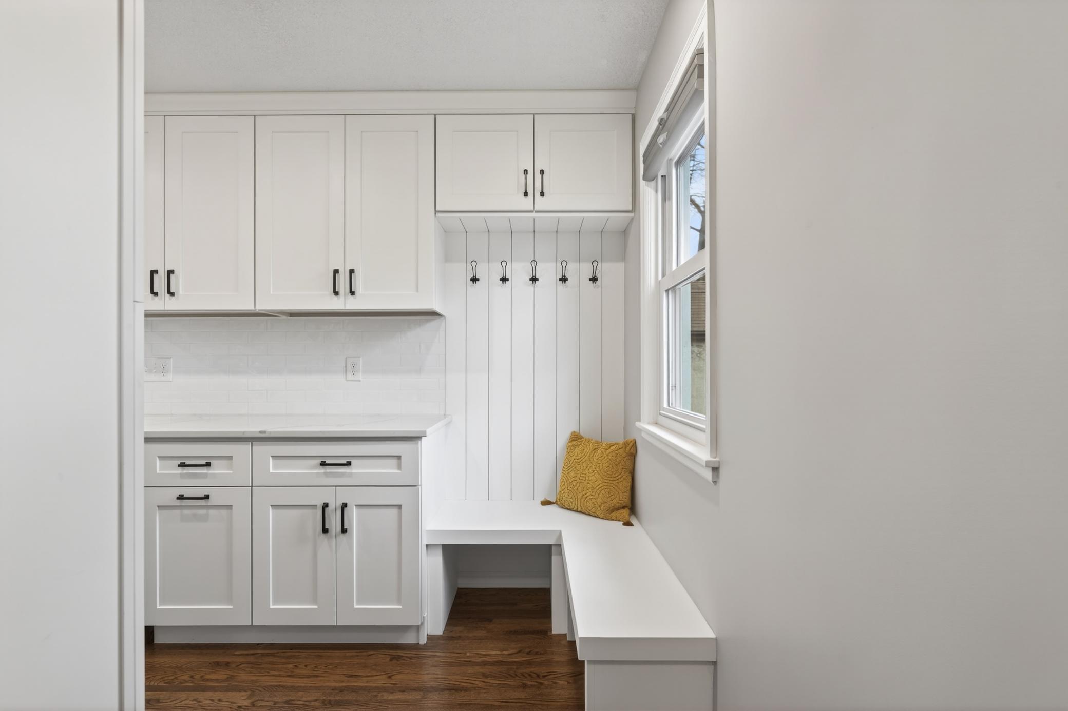 Thoughtful drop zone with bench and hooks right upon entering from the garage.