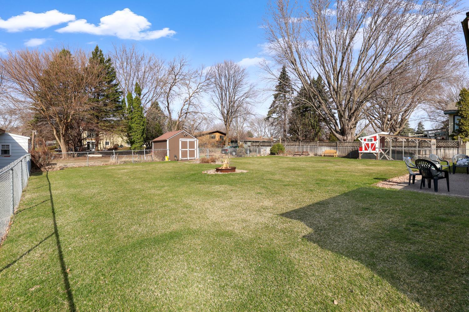 Private, flat backyard with two sheds for extra storage, a fire pit for gathering, and plenty of space to enjoy outdoor living all season long.