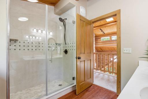 An upper-level 3/4 bath featuring a dual-sink vanity and walk-in shower, blending everyday convenience with warm log-home character.
