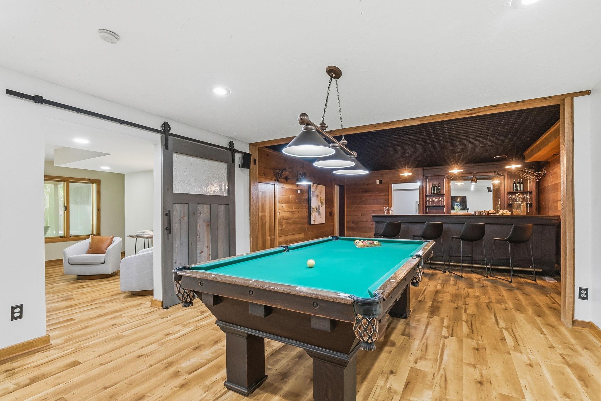 An entertainer’s dream lower level featuring a custom bar, dedicated billiards area, and expansive lounge space; perfect for hosting unforgettable gatherings and creating a true at-home retreat.