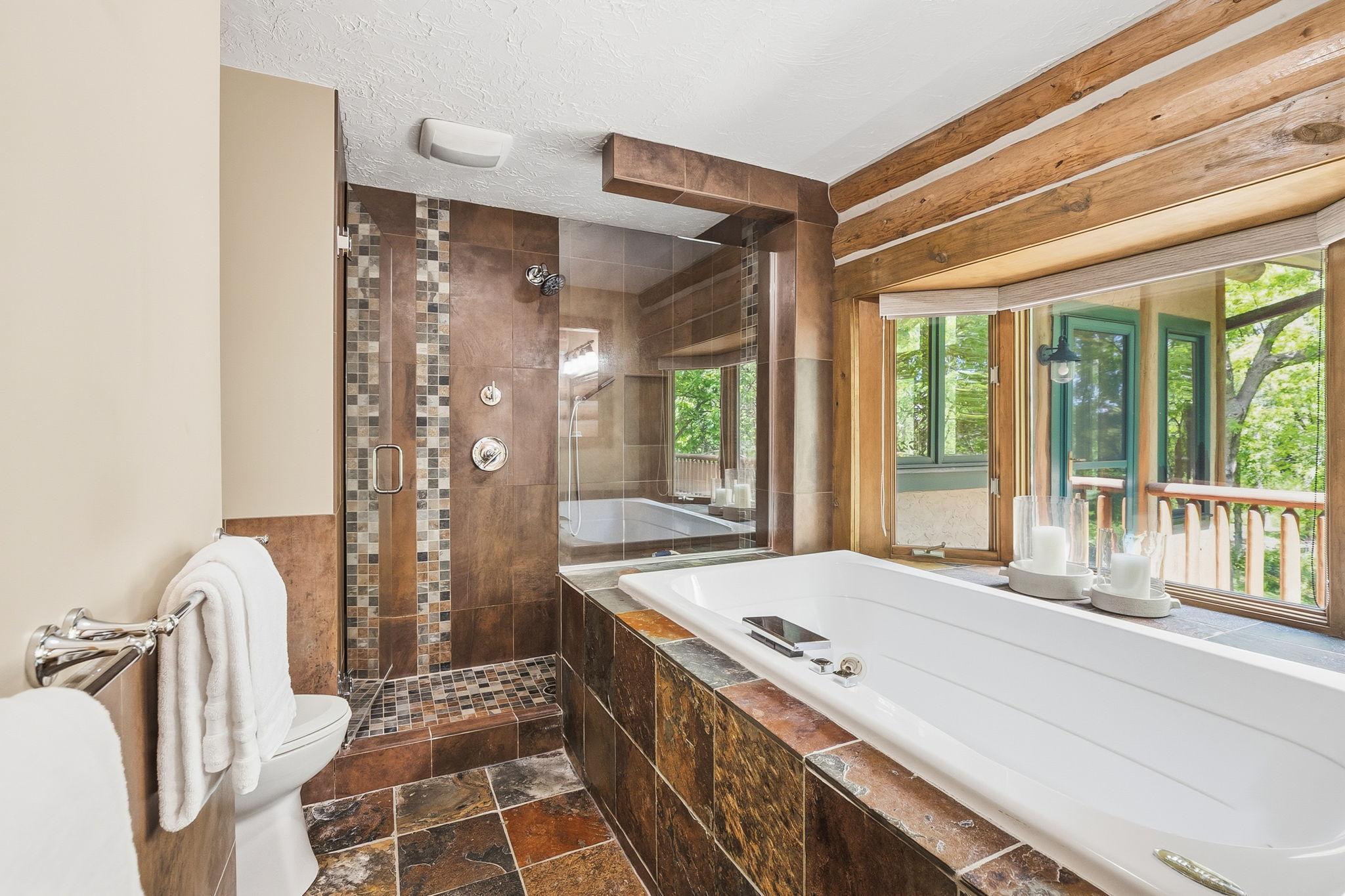 A spa-inspired ensuite featuring a soaking tub, walk-in tiled shower, and dual vanity, complemented by a spacious walk-in closet; creating a private, well-appointed retreat designed for both comfort and everyday functionality.