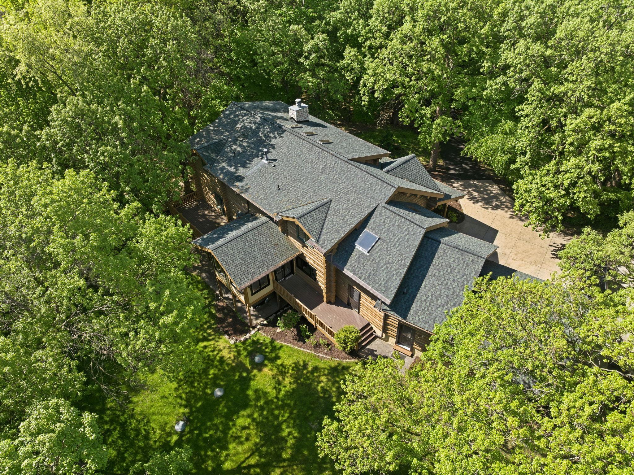 A stunning log home set on a picturesque, tree-lined lot, featuring a welcoming front porch and expansive driveway; offering a perfect blend of privacy, presence, and timeless curb appeal.