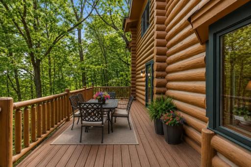 An expansive deck overlooking a serene, tree-lined backyard; offering the perfect setting for outdoor dining, relaxation, and enjoying peaceful, nature-filled views (virtually staged)