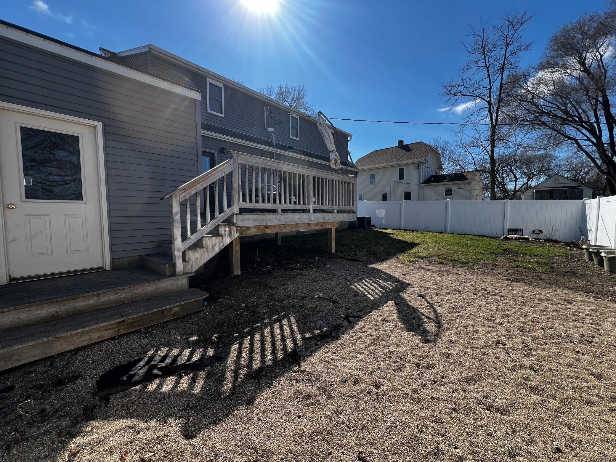 Back yard with Vinyl Fence, Deck and Door to the Garage.