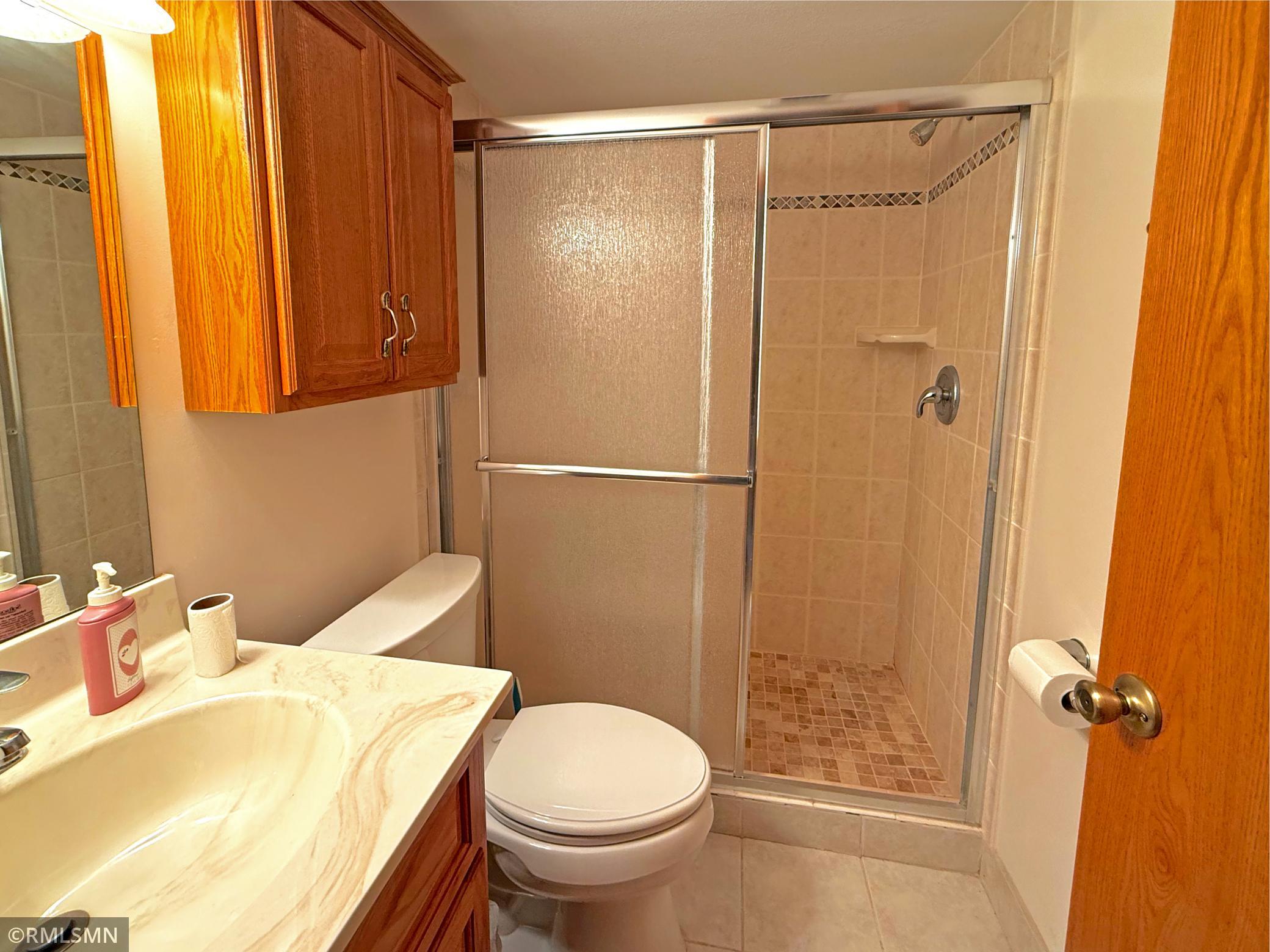 The lower level three-quarter bathroom is clean and functional, featuring a tiled walk-in shower for added convenience.