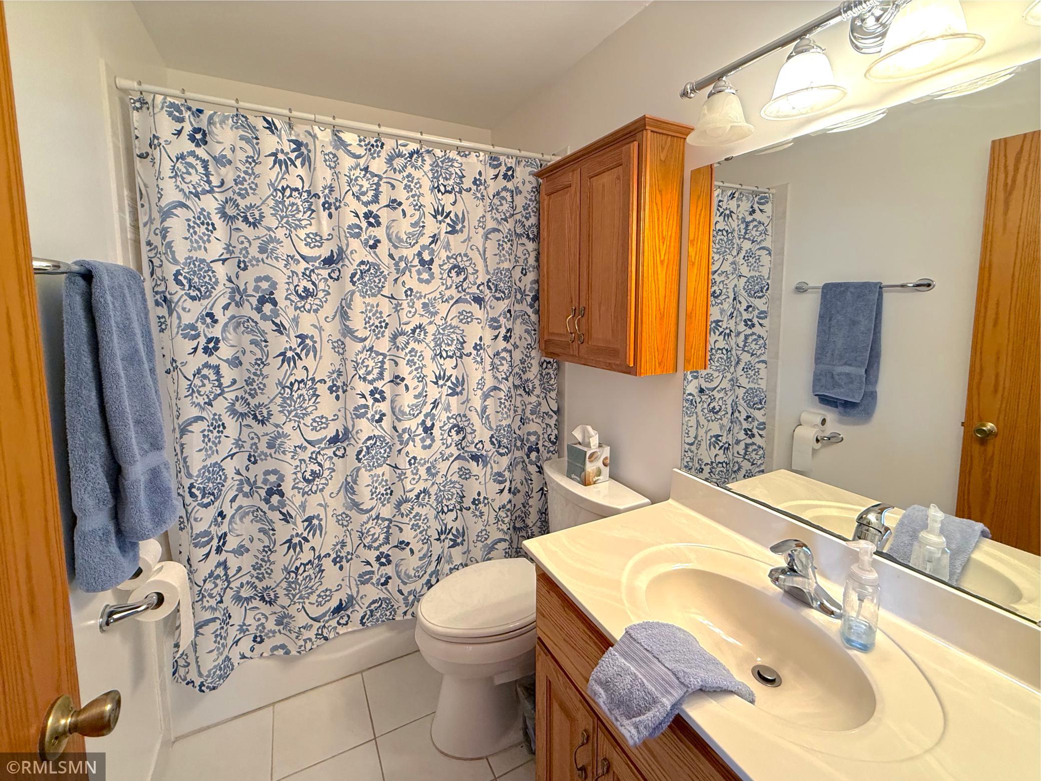 The full bathroom is bright and well-maintained, featuring a spacious vanity with ample counter space and storage below.
