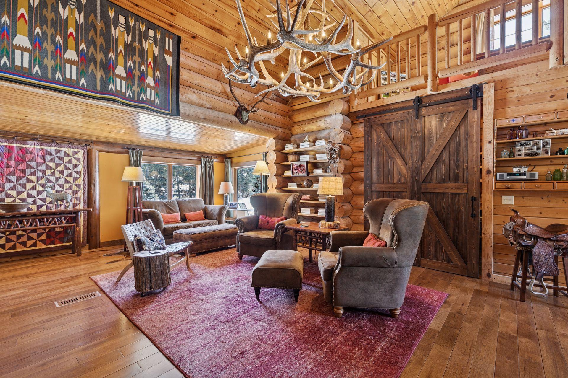 The living room features a vaulted ceiling adorned with a custom elk antler chandelier, creating a striking centerpiece that blends rustic charm with elegance.
