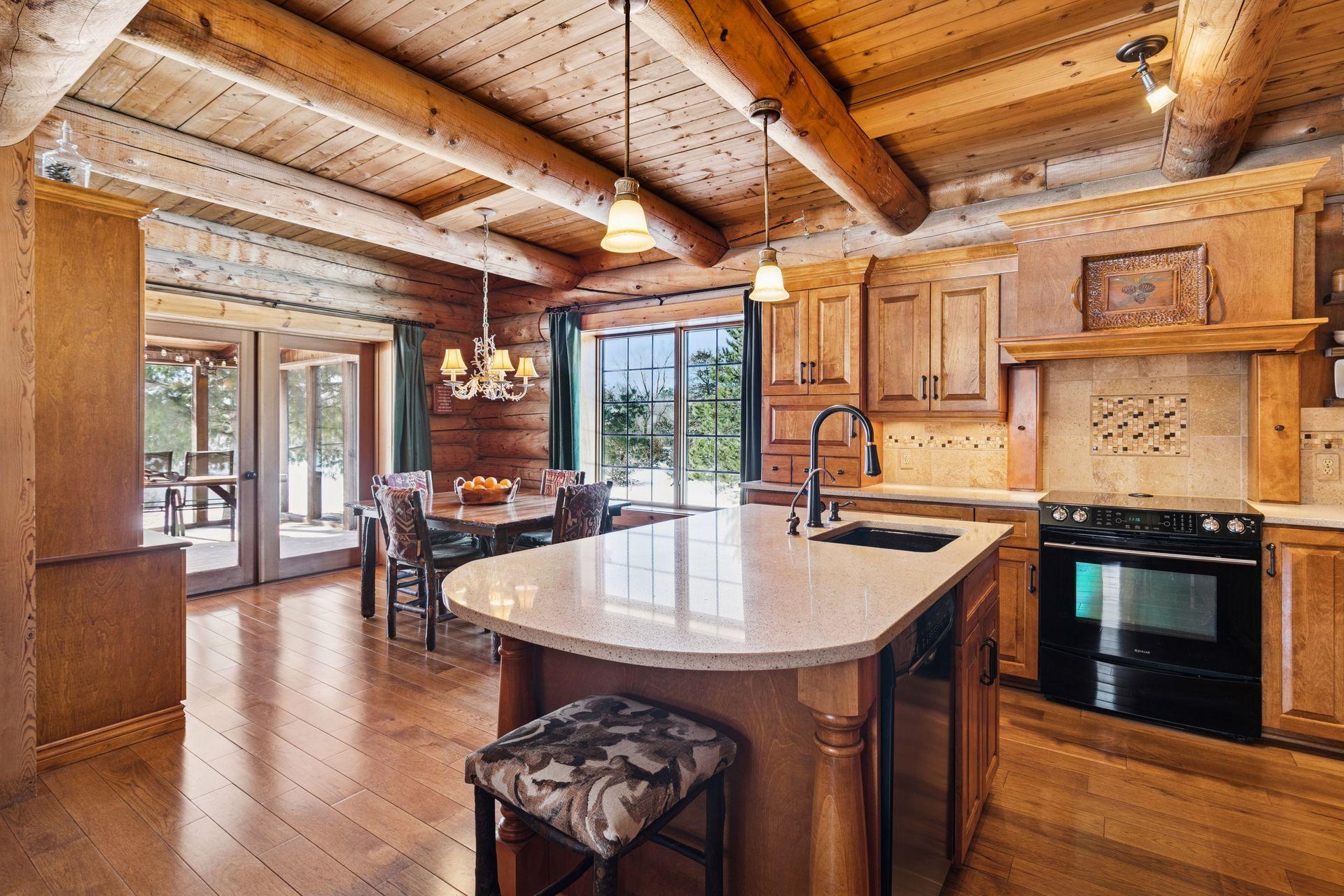 The kitchen features a convenient breakfast bar with a built-in sink and is highlighted by a custom hood vent over the stove, combining functionality with handcrafted style.