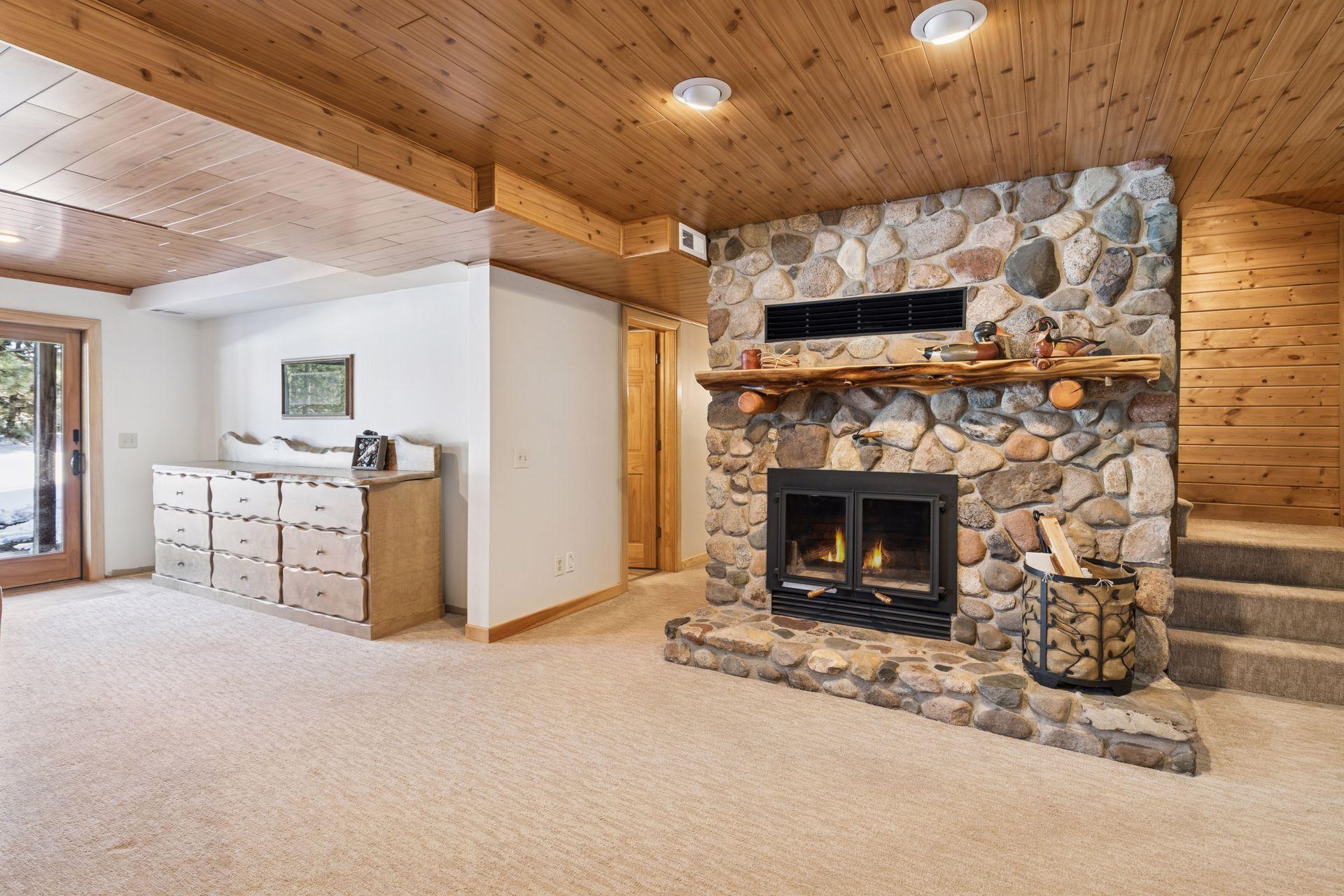 The lower-level family room also features a fieldstone finish, adding rustic charm and continuity with the natural elements found throughout the home.