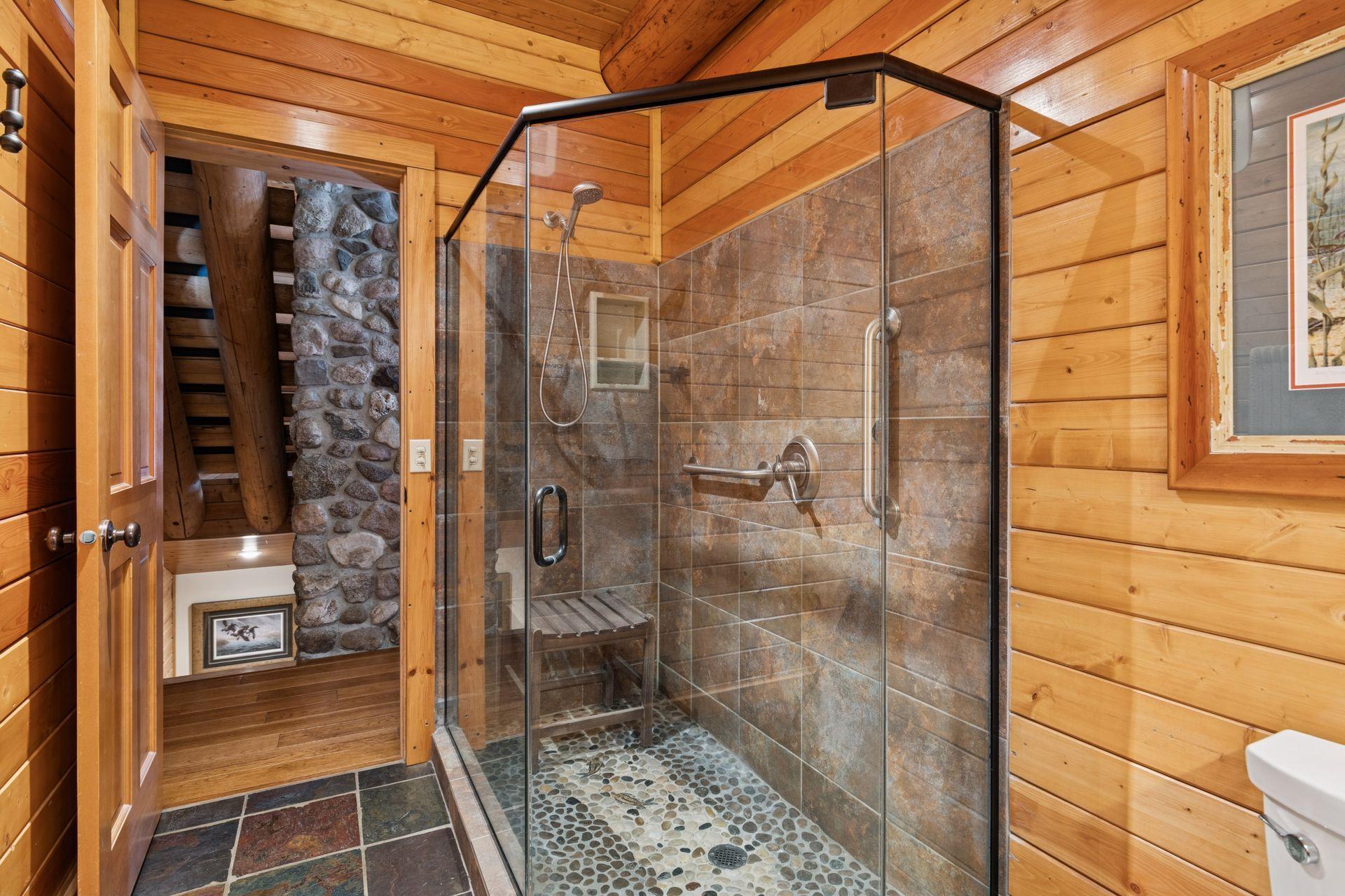 The main-level 3/4 bath features a striking rock-finished shower floor, bringing natural texture and a rustic, earthy charm to the space.