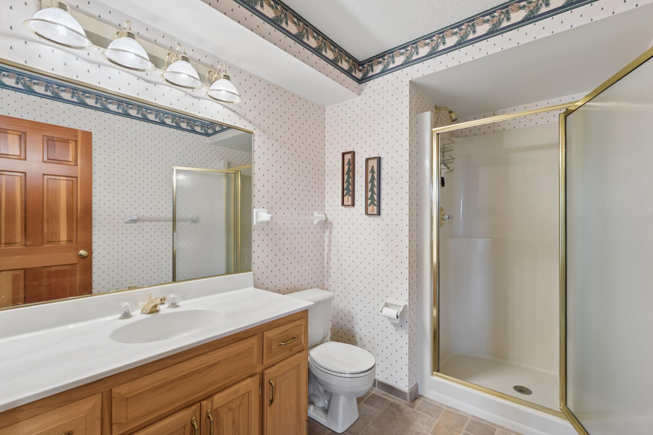 The 3/4 bath located off the kitchen in the walk-out lower level featuring a walk-in shower and large vanity.