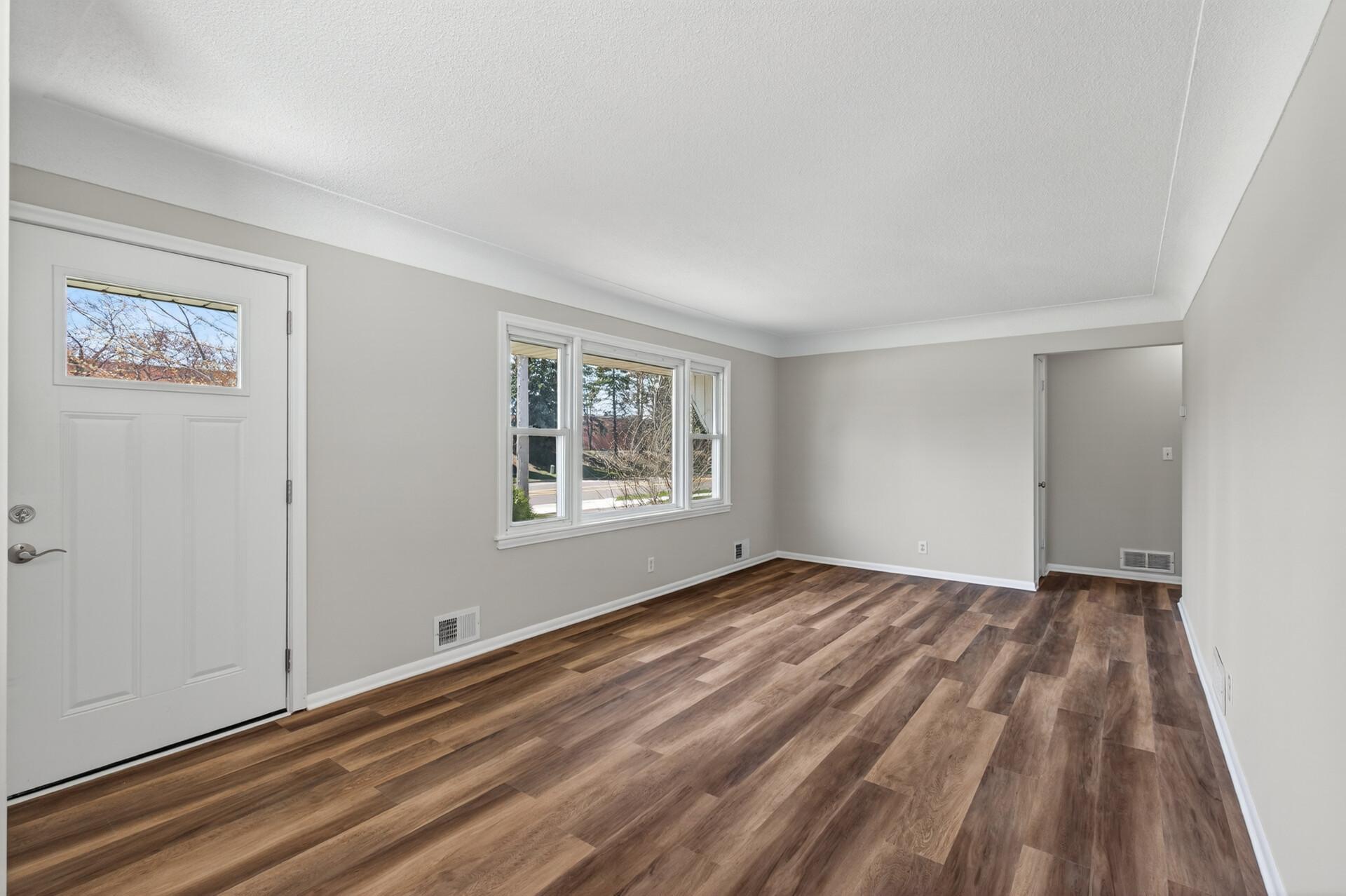 The living room showcases rich flooring complemented by neutral paint, creating the perfect canvas for your personal style.