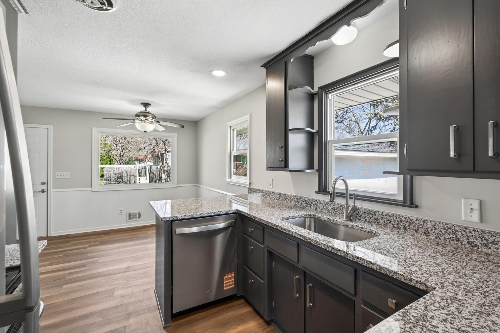 The kitchen features dark, moody cabinetry paired with sleek hard surface countertops and updated hardware.