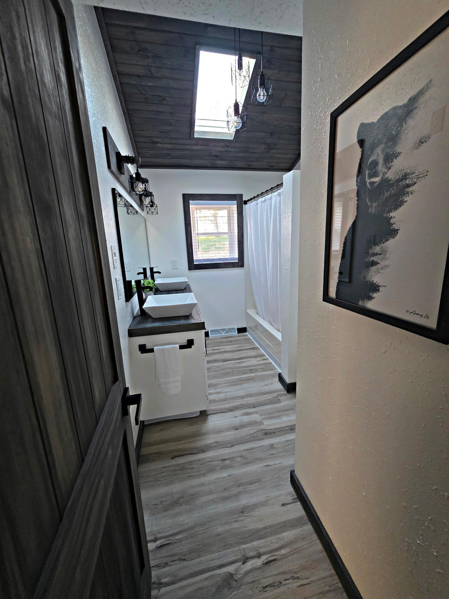 The main floor bathroom boasts tall ceilings, a skylight, and beautiful wood ceiling accents.