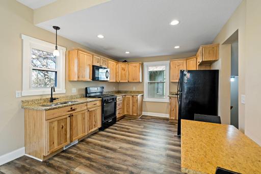 This bright and inviting kitchen features granite countertops, luxury plank vinyl flooring, and abundant natural light from two windows, complemented by recessed lighting.