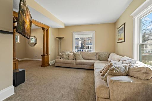 This inviting living room offers a comfortable and spacious layout with plush carpeting and abundant natural light from large windows. The open flow creates a welcoming space perfect for relaxing or gathering with guests.