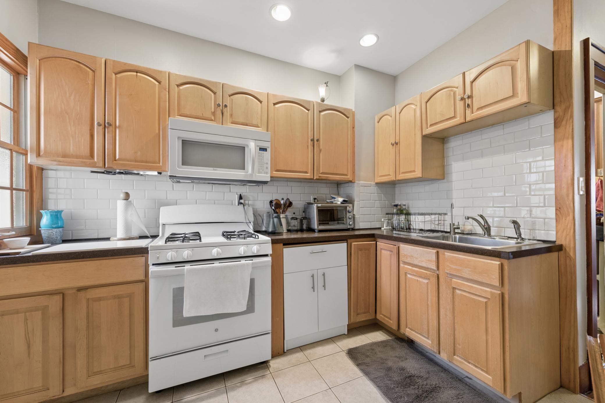 Inviting kitchen with wood cabinets, white appliances
