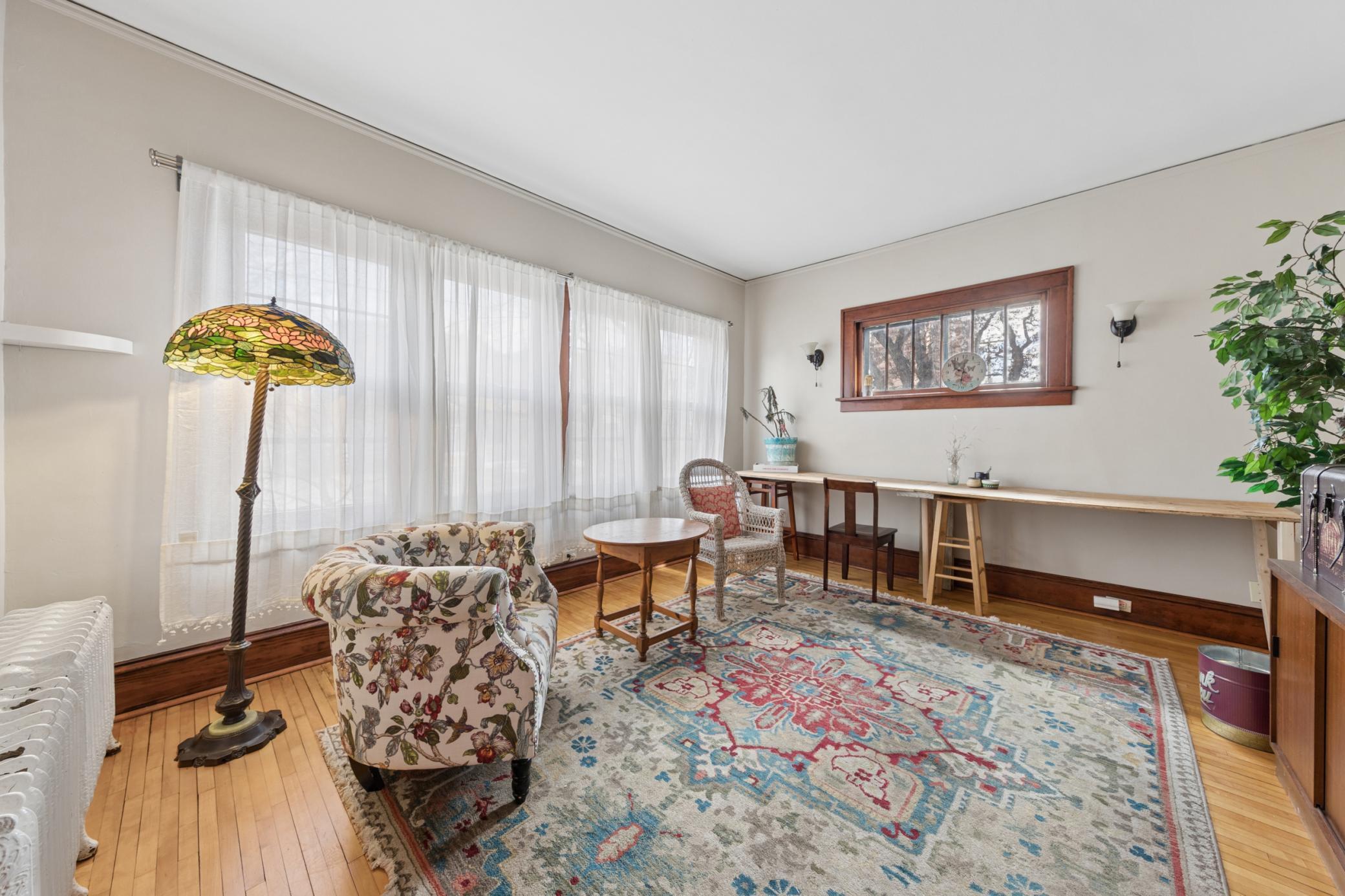 Bright, inviting living room featuring large windows, warm natural light, hardwood floors.