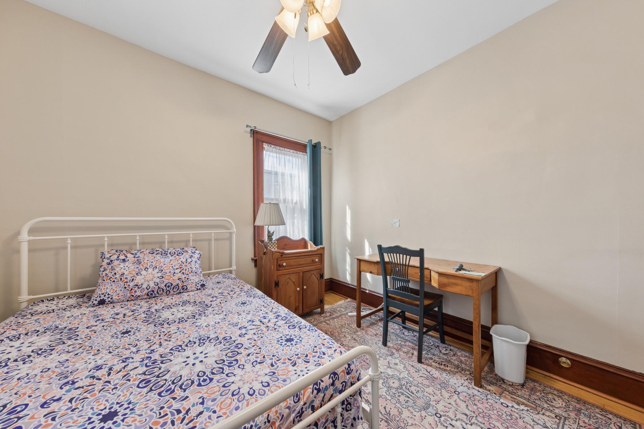 Cozy bedroom with natural light, hardwood floors, and space for a desk or reading nook