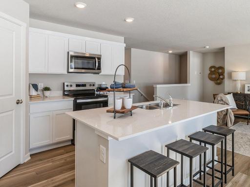 Kitchen with walk-in pantry and stainless-steel appliances. Model home shown.