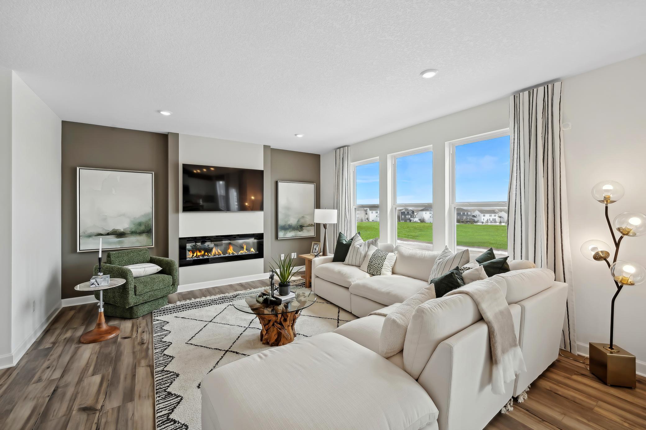(Photo of model home, finishes will vary) The spacious family gathering area seamlessly connects to the kitchen area, perfect for entertaining. It also features many large windows providing warm natural light and a fireplace.