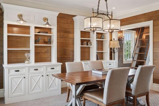 In a delightful twist, the upper-level office space features built-in shelves that not only serve as elegant storage but also conceal a hidden door leading to a secret room.