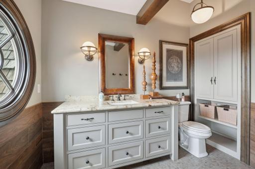 Leading into a private bathroom, this space is thoughtfully designed. The bathroom features a spacious walk-in shower, complemented by bold tile choices.