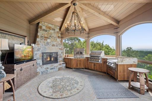 Step into the enchanting screened porch, complete with a stunning fireplace, perfect for year-round enjoyment. Featuring a built-in pizza oven, grill, and flat top. For added convenience, a hidden TV easily moves back into the cabinet space.