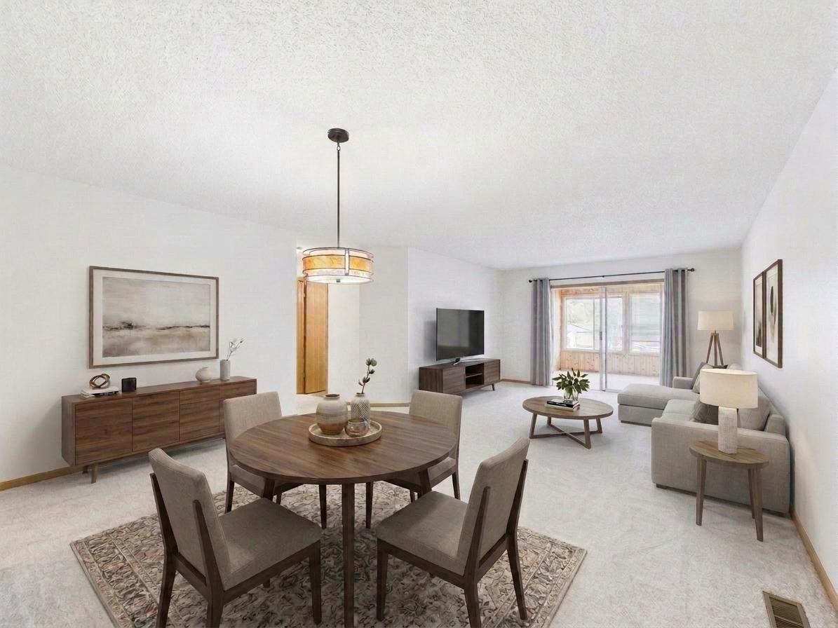 Second view of the living room, virtually staged, showing natural light and open sightlines to the sunroom