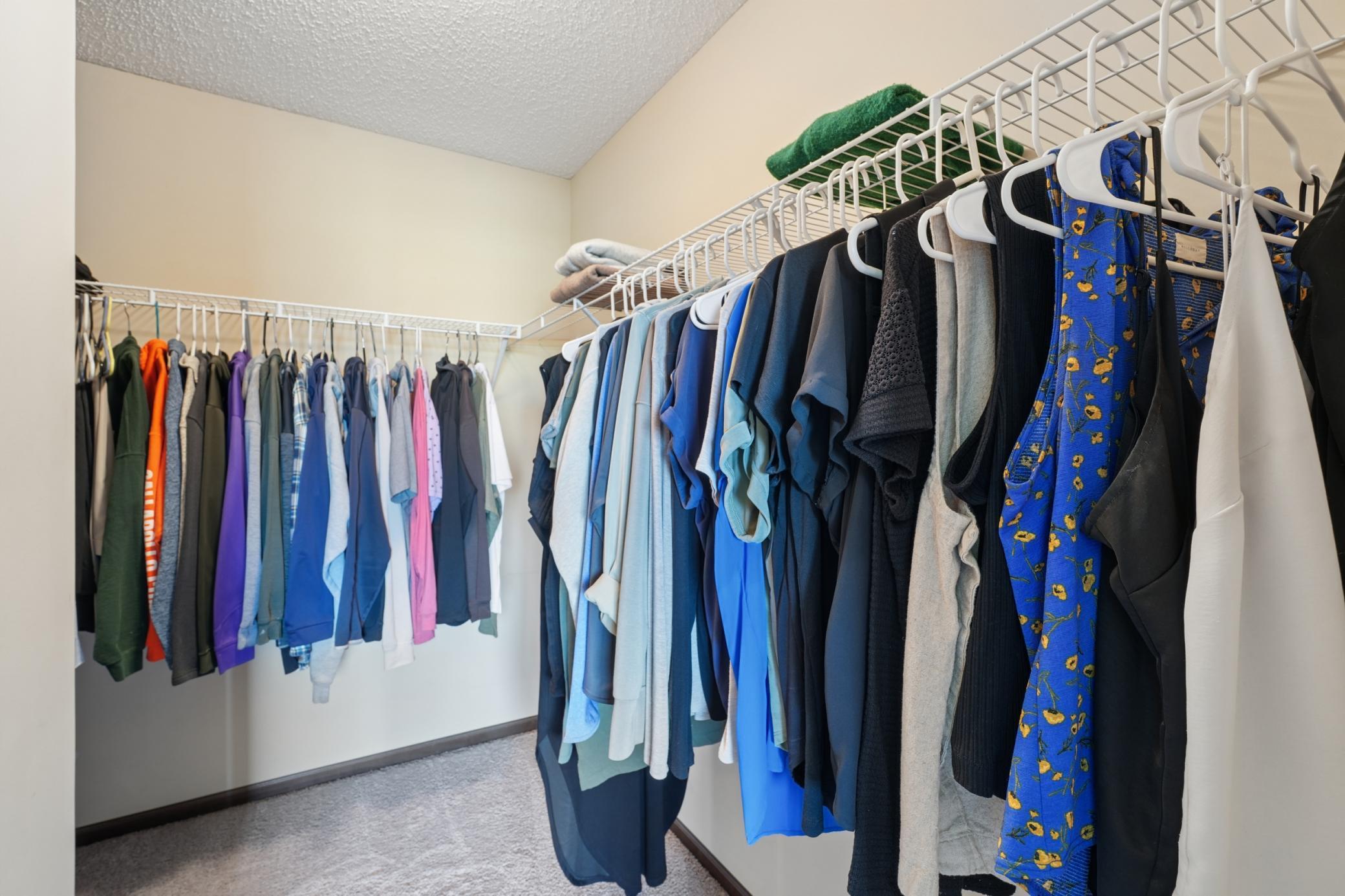 Primary suite walk-in closet with extra storage around the corner