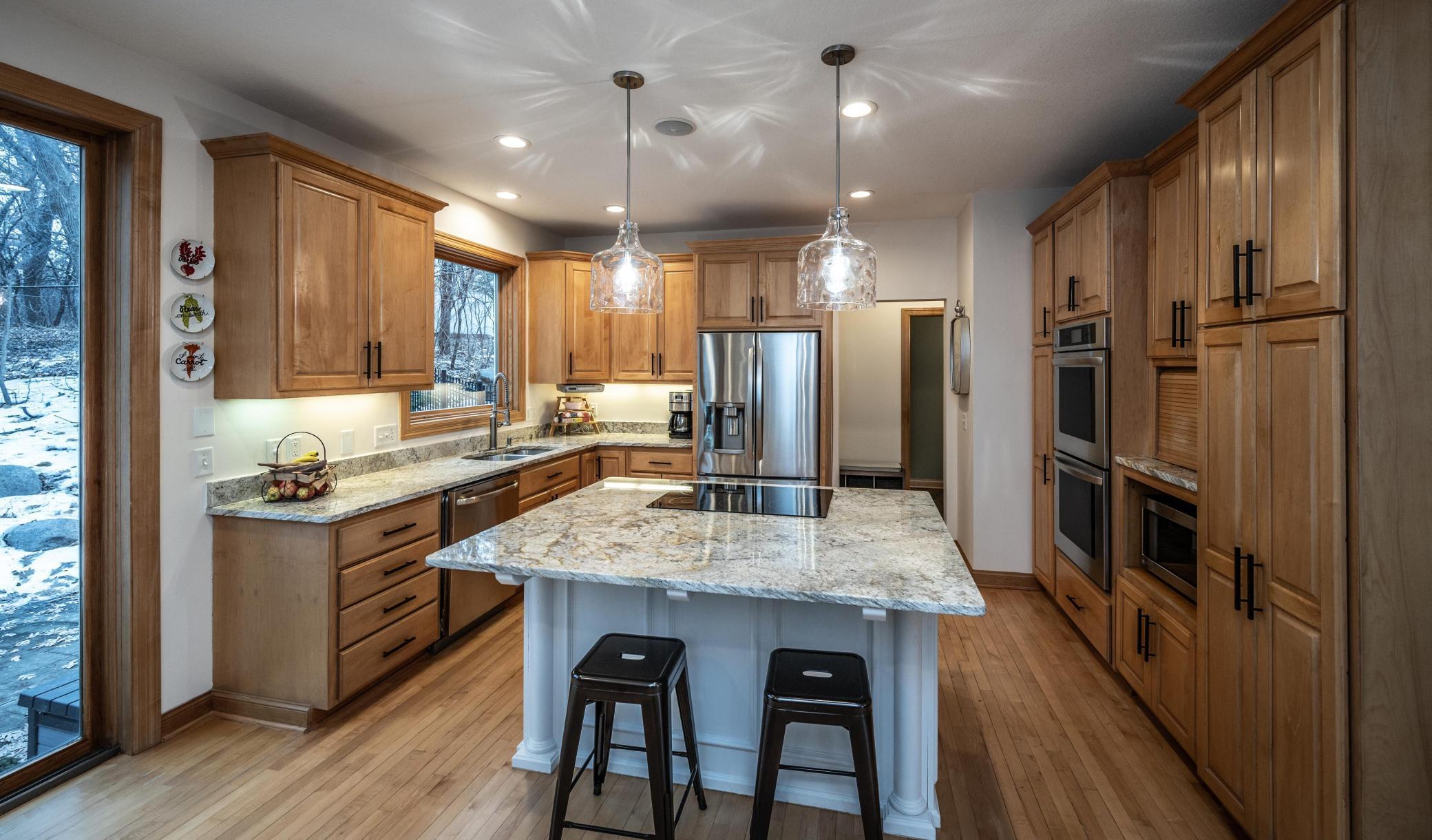 Warm maple woodwork and floors, double ovens, spacious center island w/cooktop. Very large window over the sink allows for so much light to come through.