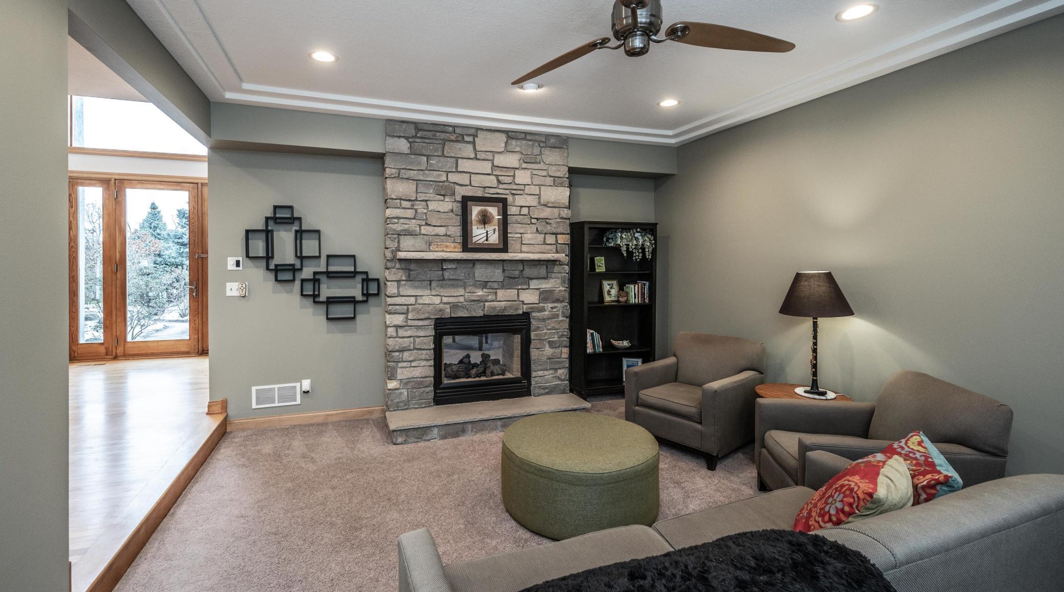 Main floor living room or family room features the cozy, stone gas fireplace, tray ceiling detail.