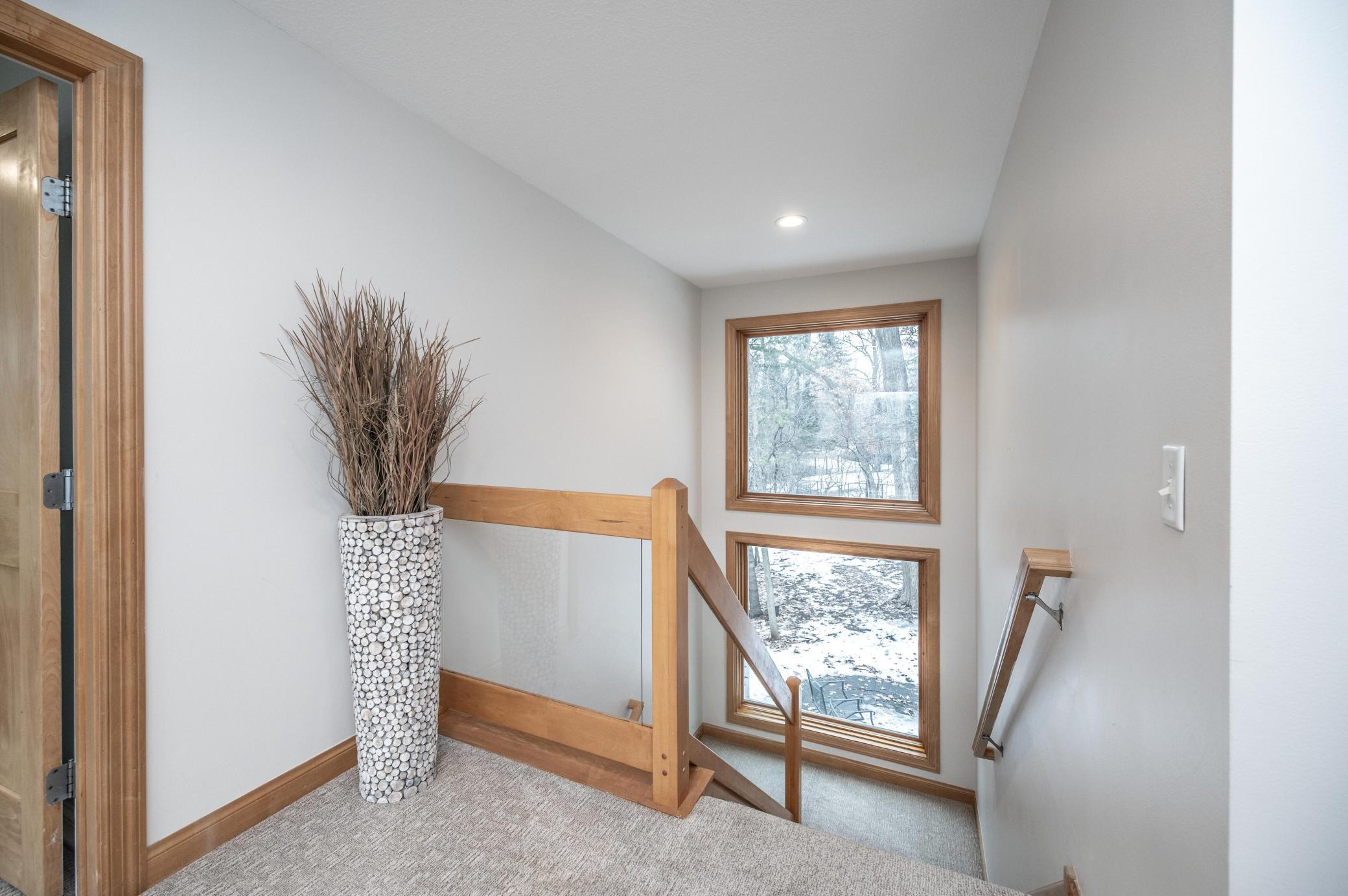 Light-filled upper level landing. Standing at the front exterior of the home, you can see all the way through the home due to the position of the windows and the railings.