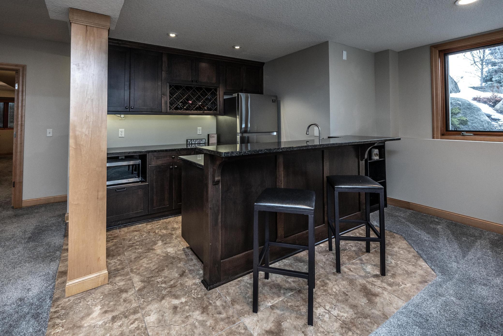 Full bar features a full-sized refrigerator and dishwasher, a microwave, wine rack and beautiful cabinetry. Imagine entertaining your friends and family in this great lower level.