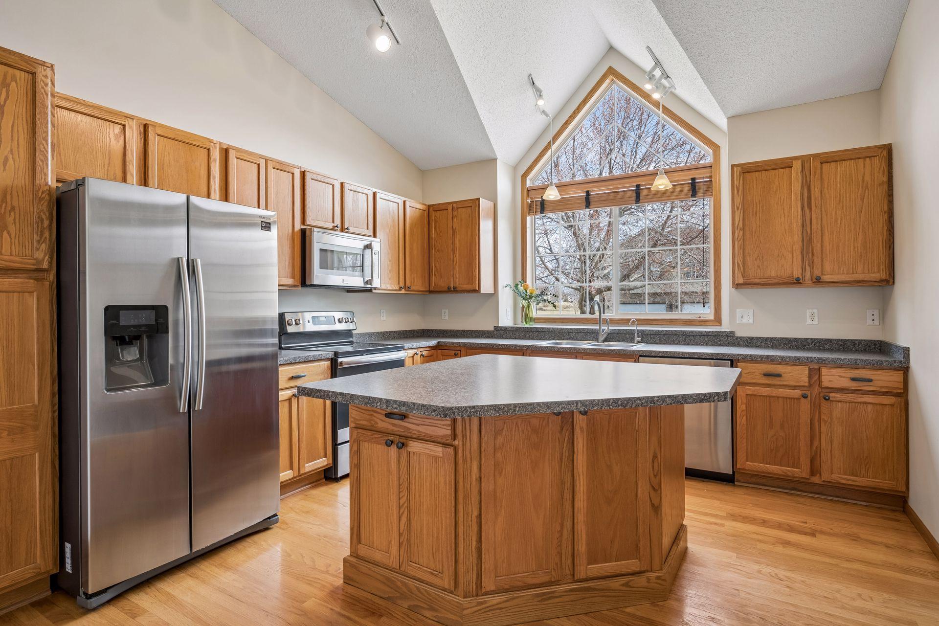 Kitchen with center island, pantry, stainless appliances and gorgeous oversized window.